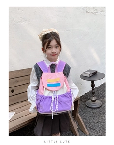 Detail of color-block kids backpack with drawstring closure worn by a young girl outdoors
