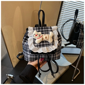 Close-up of lace trim and cute white cat doll on a black and white checkered backpack