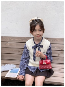Detailed view of red polka dot mini handbag paired with a stylish children knit vest outfit