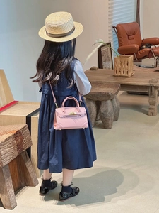 Detailed back view of pink mini crossbody bag with golden twist lock on child model