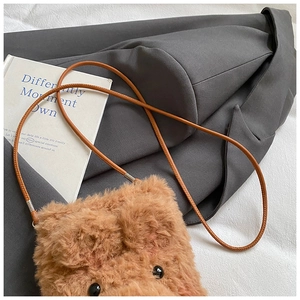 Detail of plush bear crossbody bag with soft teddy fleece and leather strap on suit