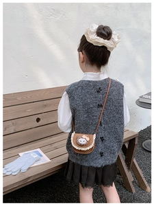 Vue arrière d'enfant portant un sac bandoulière marron avec dentelle et motif de chat