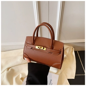 Detailed view of brown litchi grain leather texture and golden metal twist lock on mini handbag