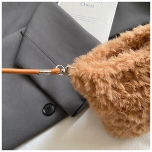 Detail of brown faux fur texture and leather strap with silver metal buckle on bear bag