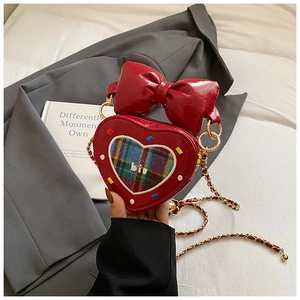Détail du sac cœur rouge avec nœud, chaîne métallique et patch à carreaux pailleté