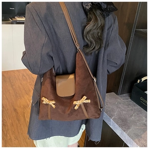 Détail du sac cabas en daim marron avec nœuds léopard et rabat porté par le mannequin