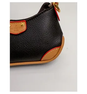 Gros plan détaillé du sac en cuir grainé avec coutures rouges et rivets métalliques dorés
