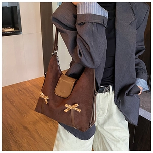 Détail du sac hobo en daim marron foncé avec nœuds léopard et fermeture à rabat magnétique