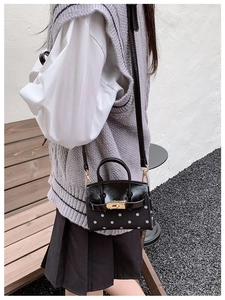Detailed view of polka dot mini handbag featuring golden metal twist lock and leather strap