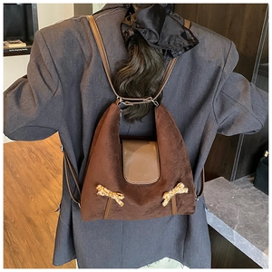 Détail d'un sac à dos en peluche marron foncé pour enfants avec nœuds et rabat en cuir