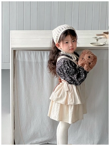Detail view of a floral top and layered cream suspender dress in a rustic Korean style
