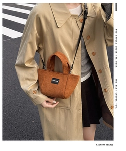 Détail du sac seau enfant en velours marron montrant la texture et l'étiquette cuir