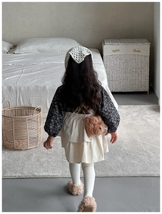 Rear view of a girl wearing a teddy bear crossbody bag with floral dress and vest