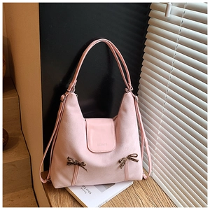 Détail du sac à bandoulière en daim rose avec nœud léopard et logo sur une table en bois