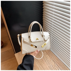 Close-up of cream leather mini handbag with gold metal lock and litchi texture