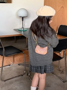 Close-up of pink and brown mini dumpling bag with gold chain on a young model