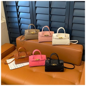 Macro detail of six colorful mini leather handbags with gold clasps on a brown leather bench