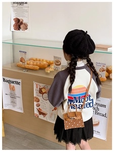 Detail of mini brown polka dot handbag with gold lock on child's fashion outfit