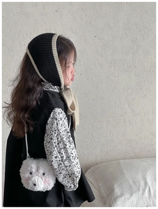 Close-up of a cute white plush bear crossbody bag styled with a warm winter knit hat