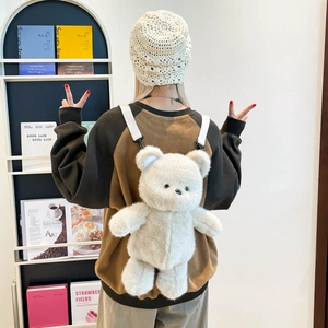 Cute white plush bear backpack for children shown being worn by a model in a library