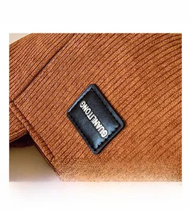 Gros plan sur la texture velours côtelé marron avec un écusson rectangulaire en cuir noir