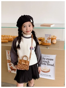 Polka dot mini handbag for kids with metal lock closure shown in a lifestyle bakery setting