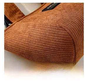 Gros plan détaillé de la texture du velours côtelé marron et du logo en cuir d'un sac seau
