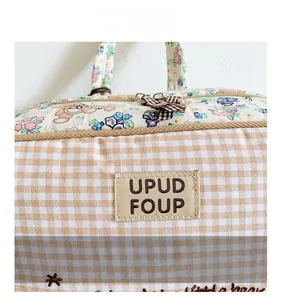 Detail of quilted kids backpack featuring floral bear patterns and a premium leather logo tag