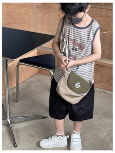 Détail de la sacoche enfant avec blocs de couleurs kaki et écusson logo arrondi