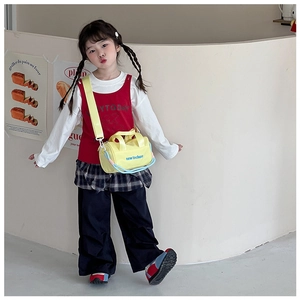 Close-up of kids casual outfit featuring a yellow bucket bag and lettered vest set
