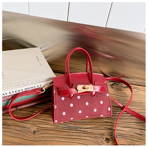 Detail of red polka dot mini bag with golden twist lock on wooden surface