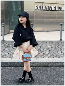Close-up of quilted denim blue mini crossbody bag with gold chain strap on a child model