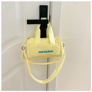 Detail view of a yellow cylindrical kids crossbody bag hanging on a door handle