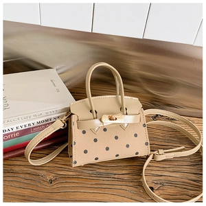 Detailed view of mini polka dot handbag with suede texture and gold buckle on wooden table