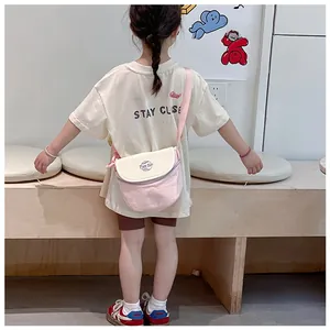 Vue arrière d'un enfant portant un sac à bandoulière en toile rose et crème avec texte