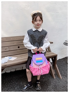 Outdoor shot of a colorful color-block children's backpack with drawstring and flap closure