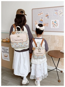 Detail view of parent-child floral backpacks with teddy bear charms in two sizes