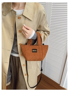 Sac seau en velours côtelé marron avec patch logo porté par un mannequin stylé