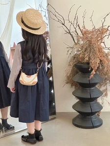 Rear view of a girl wearing a navy dress with a beige and brown chain dumpling bag