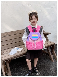 Pink and purple contrast color school backpack shown on a young girl in an outdoor setting