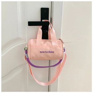Detailed shot of pink cylindrical bucket bag with purple brand logo and braided rope detail