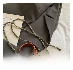 Detail of light blue quilted denim mini bag with brown trim and metal chain strap