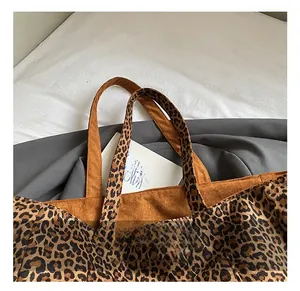 Détail de la poignée confortable du sac léopard avec surpiqûres en daim marron