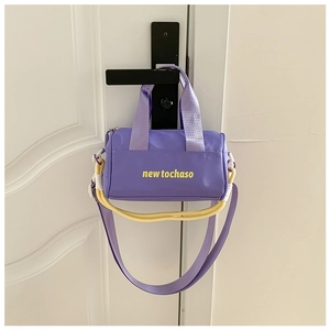 Detail of purple cylindrical nylon bucket bag with yellow contrast handle and logo