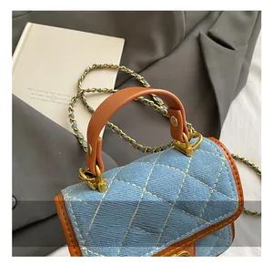Detail of blue denim quilted mini bag with brown leather trim and golden chain strap