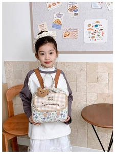 Detail of floral toddler backpack with plush bear charm and checkered flap on little girl