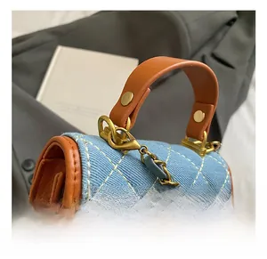 Detail shot of the blue denim quilted bag featuring brown leather trim and golden metal hooks