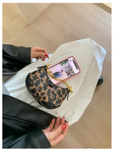 Detail view of leopard print mini half-moon bag with gold chain and black PU leather trim
