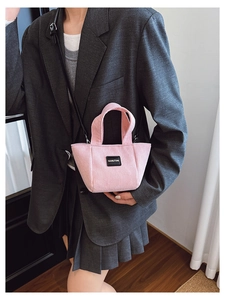 Détail du mini sac cabas en velours côtelé rose avec logo et fine bandoulière en cuir noir
