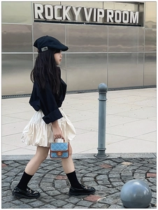 Street style shot of a girl carrying a blue quilted mini bag with golden metal hardware